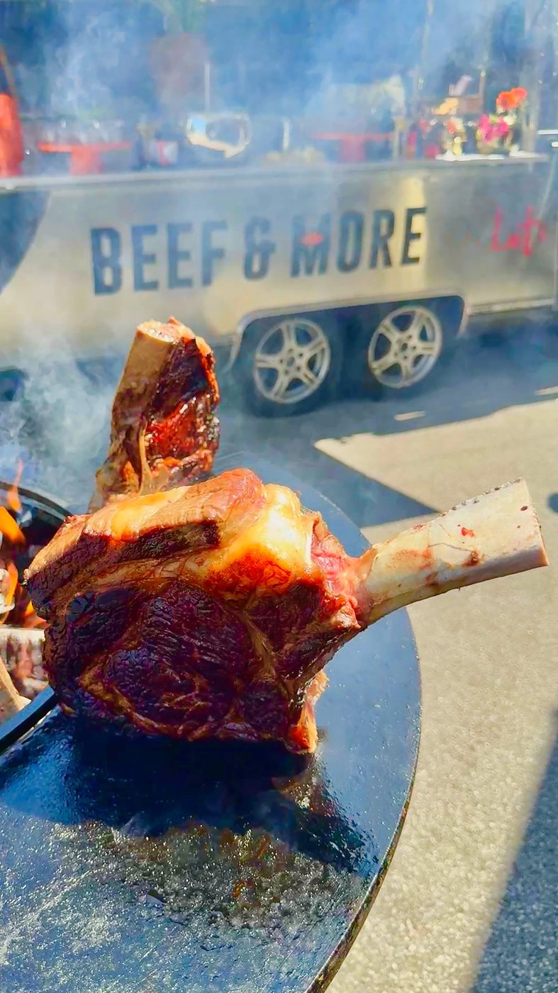 Ein Tomahawk-Steak auf dem Grill vor dem BEEF & MORE Anhänger
