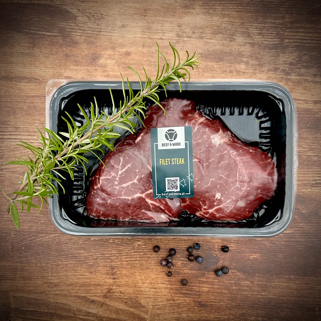 Filetsteak auf dunklem Holz mit Rosmarin und Pfeffer